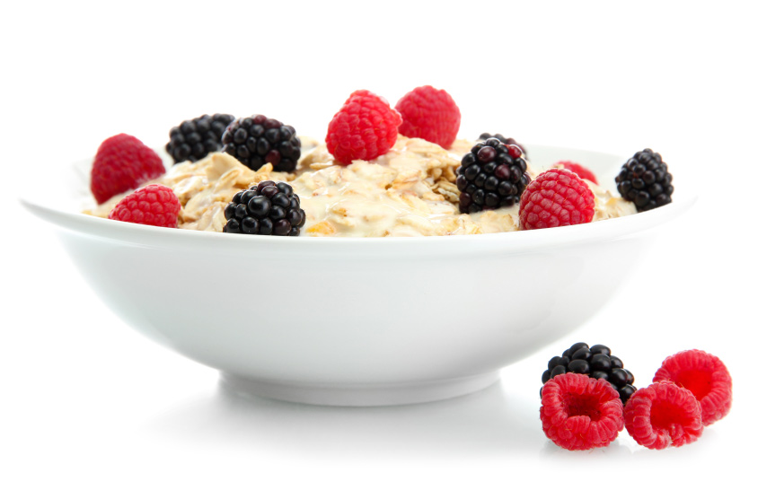 Porridge topped with berries in a white bowl against a white background. 