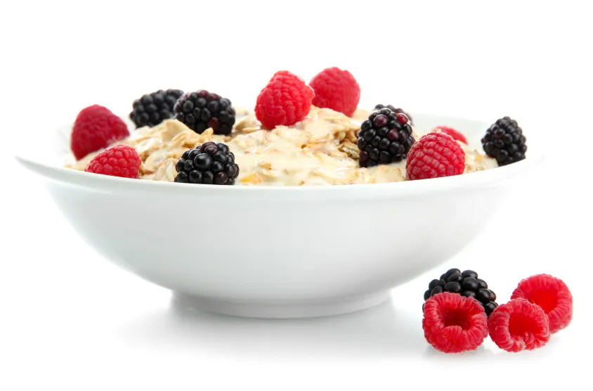 Porridge topped with berries in a white bowl against a white background. 
