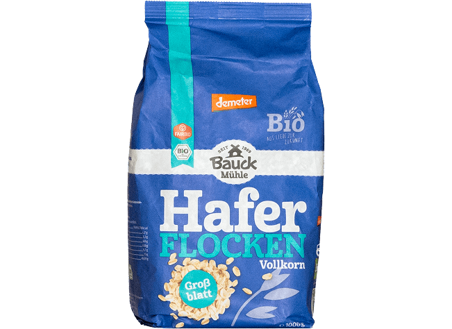 Blue wholegrain oat flakes package with brand labeling and organic seals isolated on a neutral background for product focus