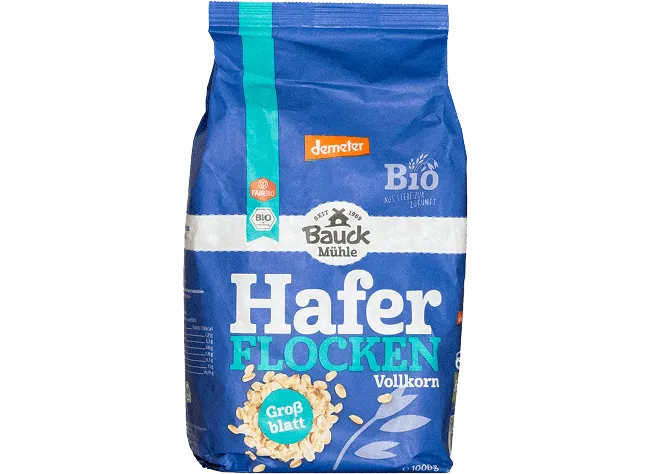 Blue wholegrain oat flakes package with brand labeling and organic seals isolated on a neutral background for product focus