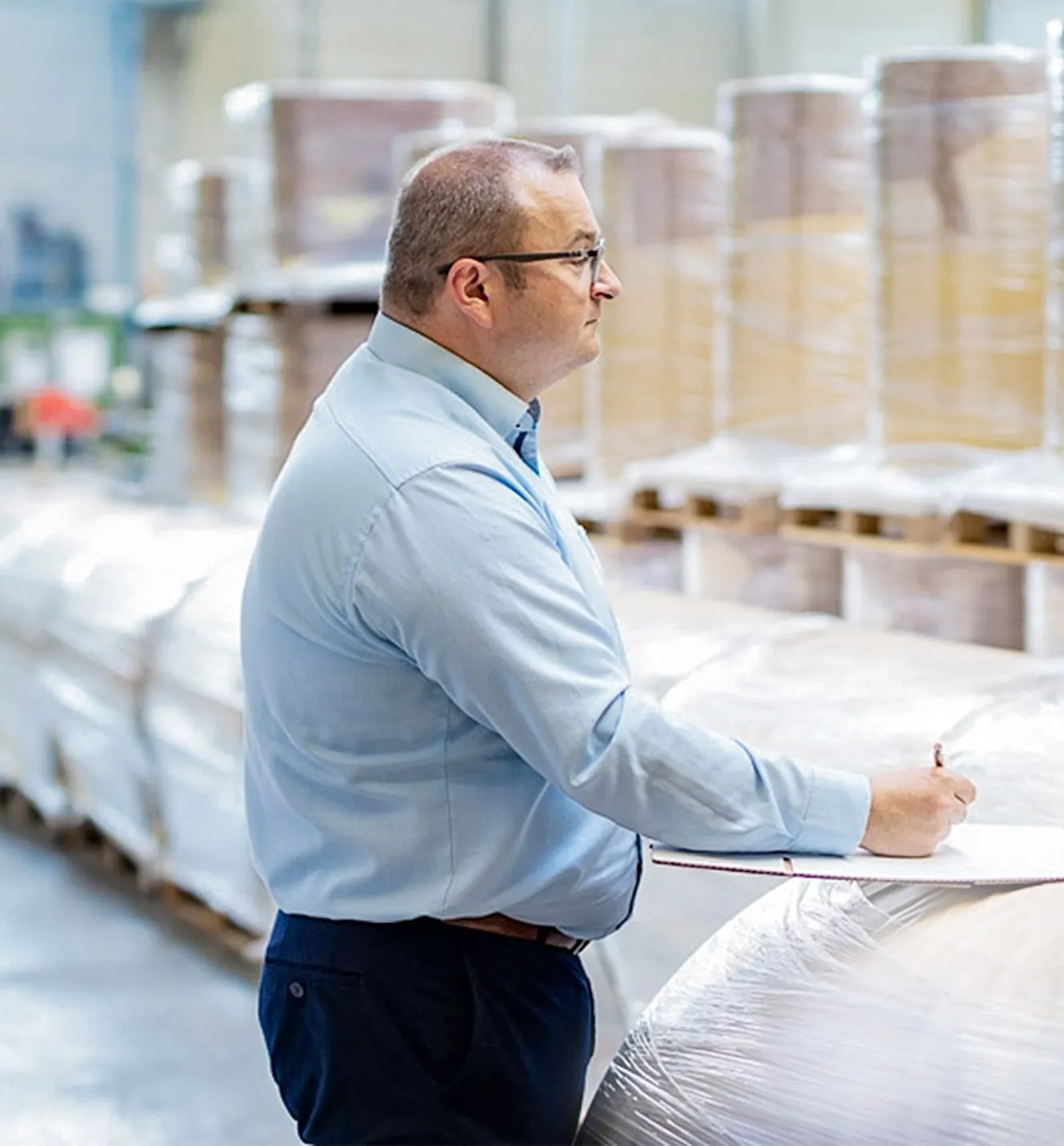 Bernhard Eberlein in a warehouse making notes on a clipboard