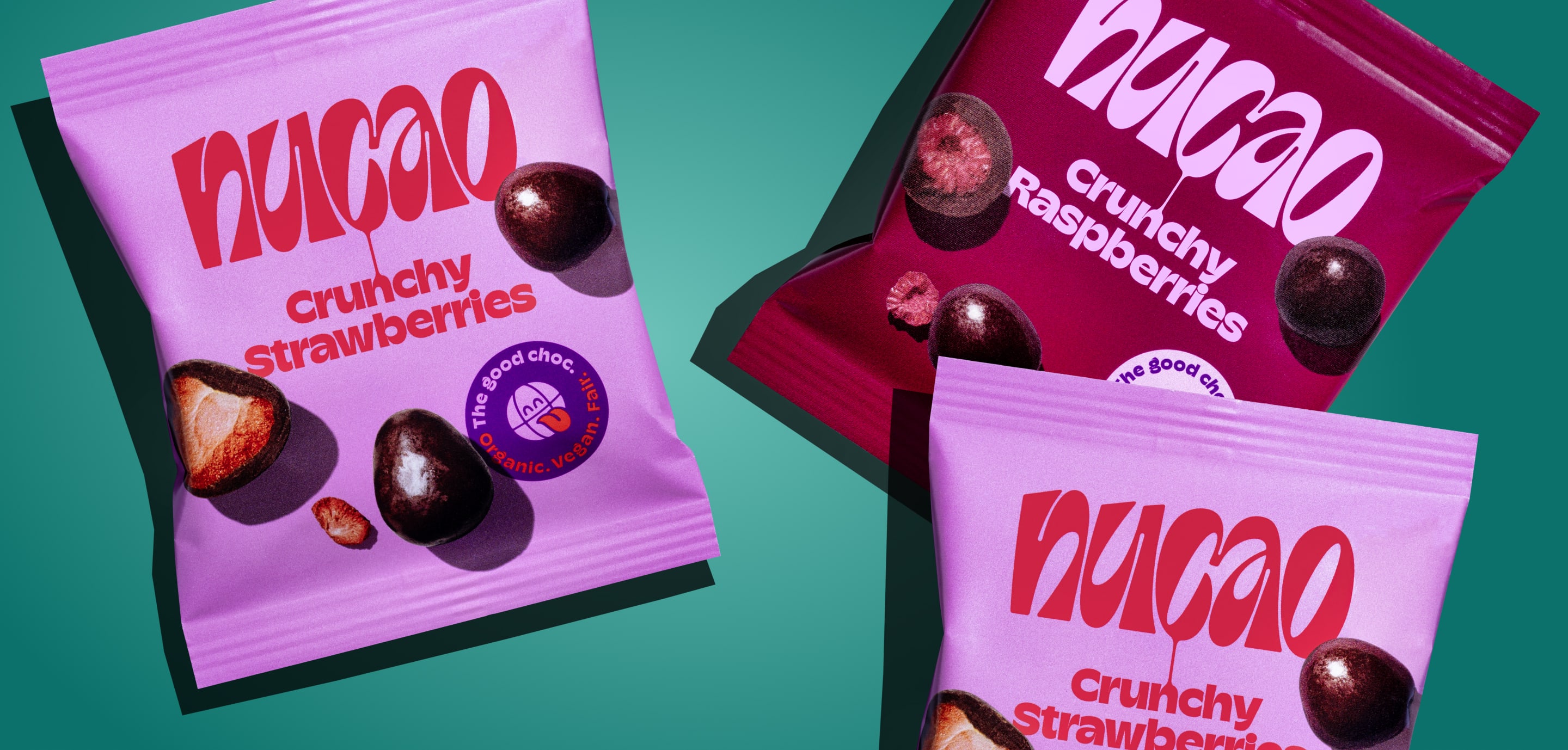 Colorful nucao snack packs for almonds, strawberries and other mixes scattered on a teal background with nuts and fruits.